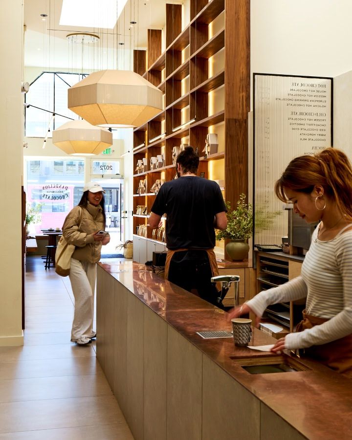 A cozy café interior with customers interacting and a barista serving.