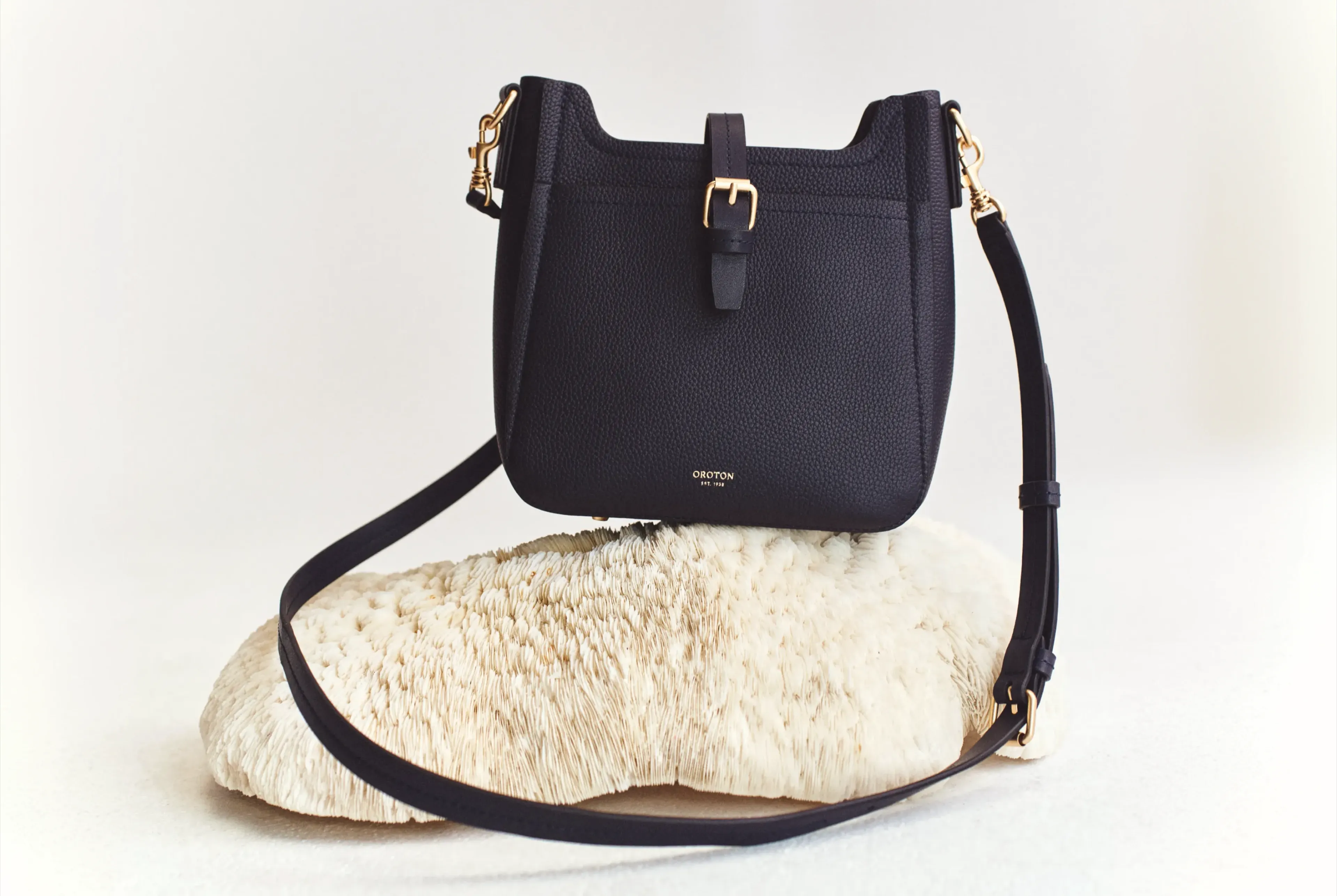 A black handbag resting on a textured stone surface.