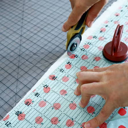 Cutting fabric with a rotary cutter and ruler on a big cutting mat