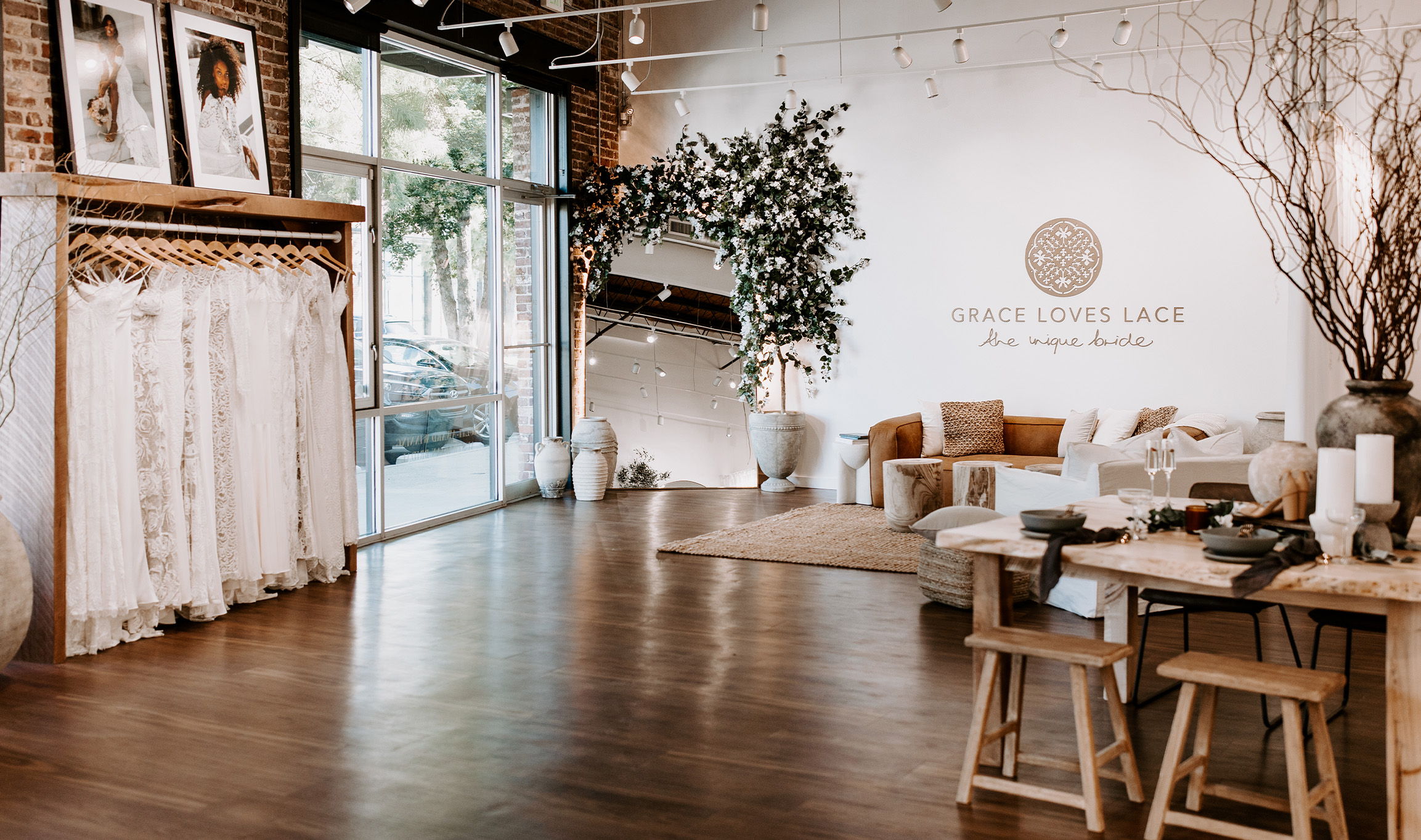 A stylish interior featuring clothing racks, furniture, and decorative plants.