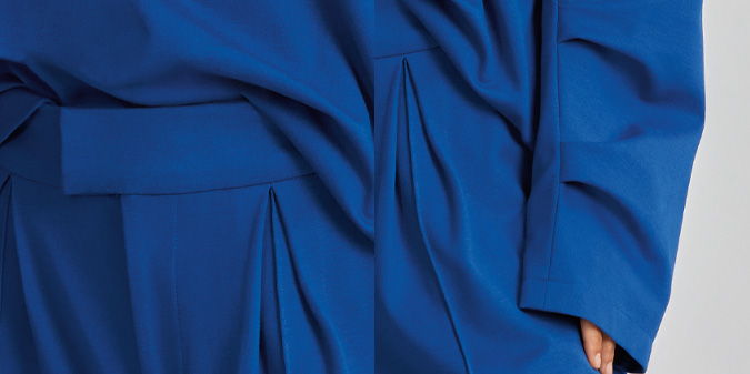 A close-up of draped blue fabric with pleats and texture.