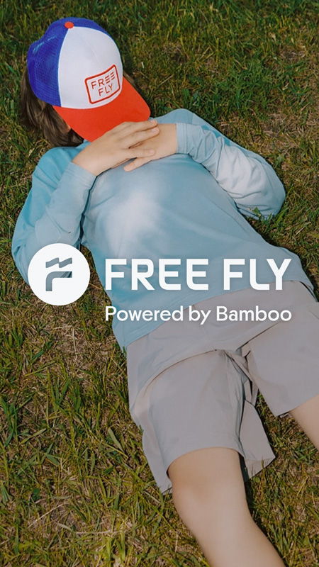 Child lying on grass wearing a cap and long-sleeve shirt.
