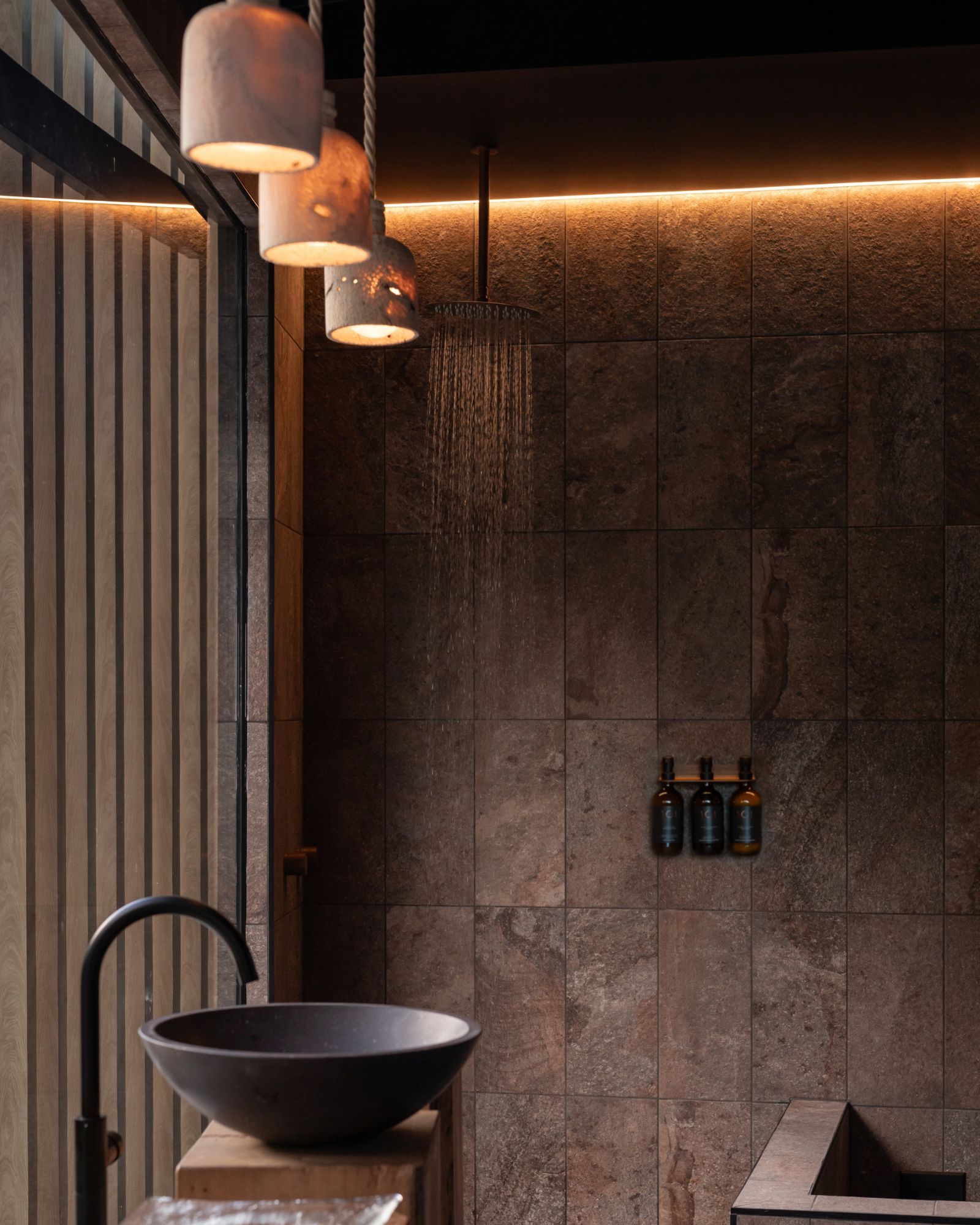 Modern bathroom with stone walls, a basin, and stylish lighting fixtures.