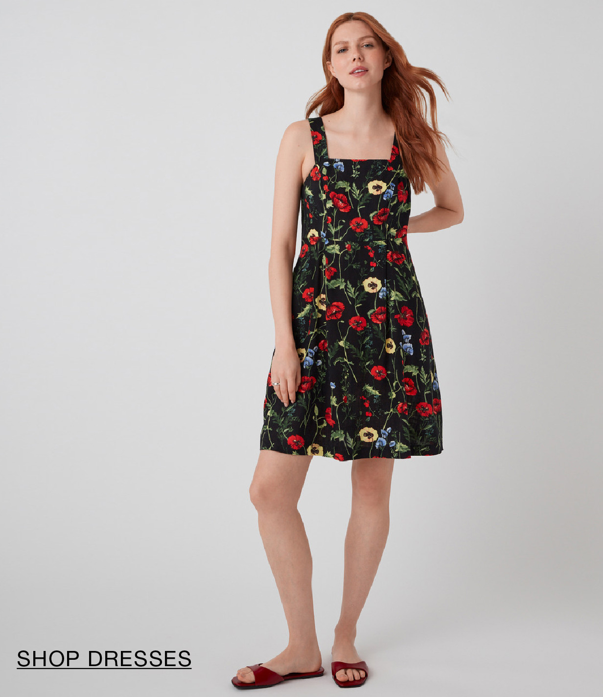 A woman in a floral dress poses against a neutral background.