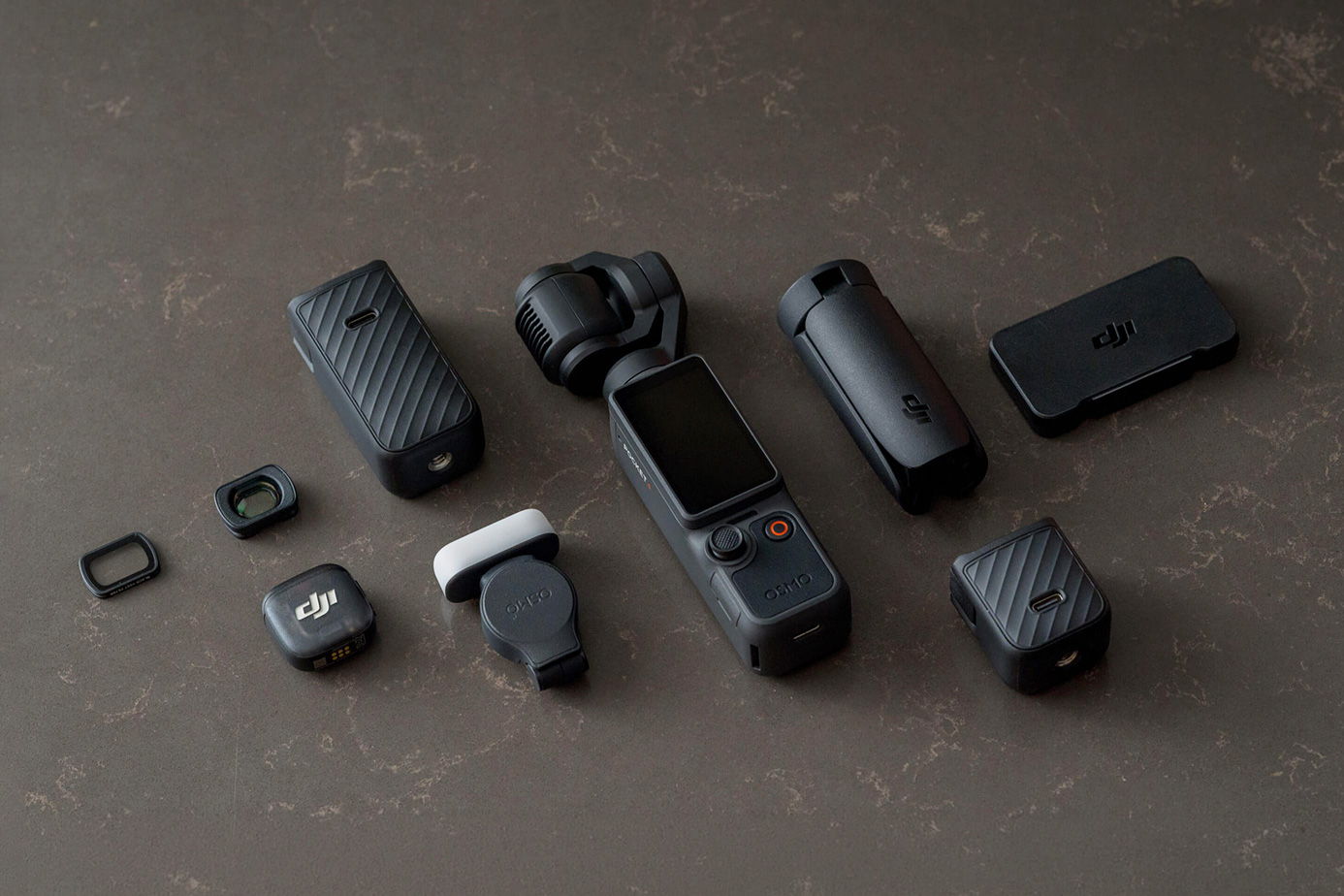 Various camera accessories arranged on a dark surface beside the Osmo Pocket 4.