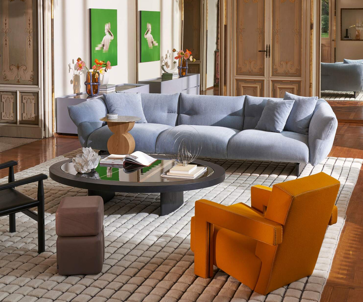 Modern living room with blue sofa, orange chair, and coffee table.