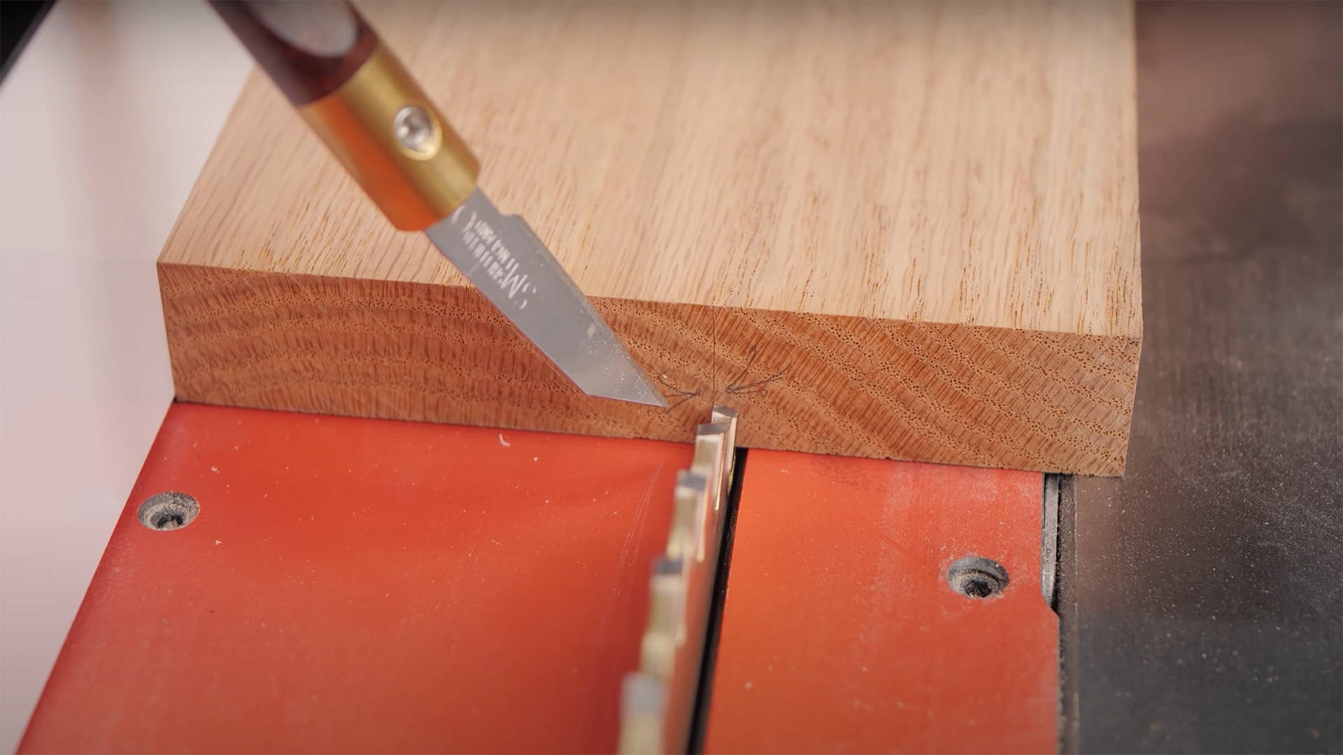 marking knife pointing at a board lined up on a table saw to cut