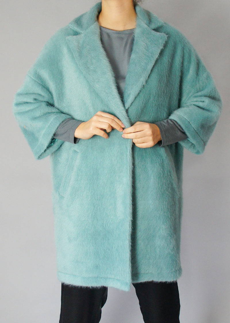 A model wearing a light teal faux fur oversized coat