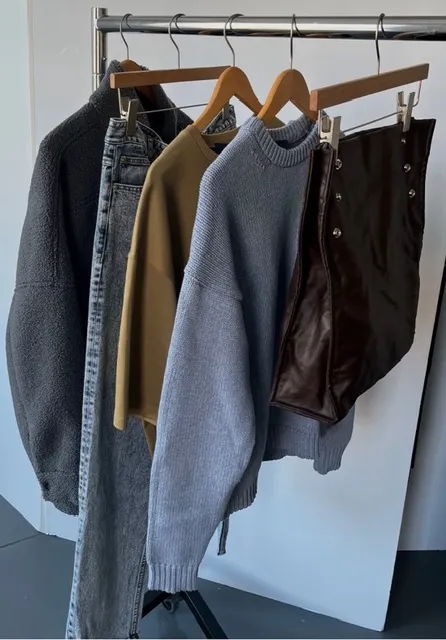 Clothes hanging on a rack, including sweaters and pants.