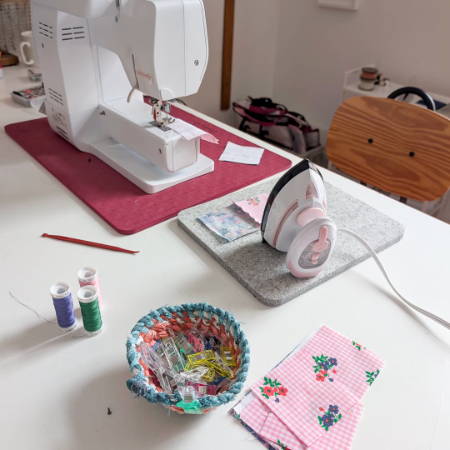 a sewing table with sewing machine, wool pressing mat and a mini iron