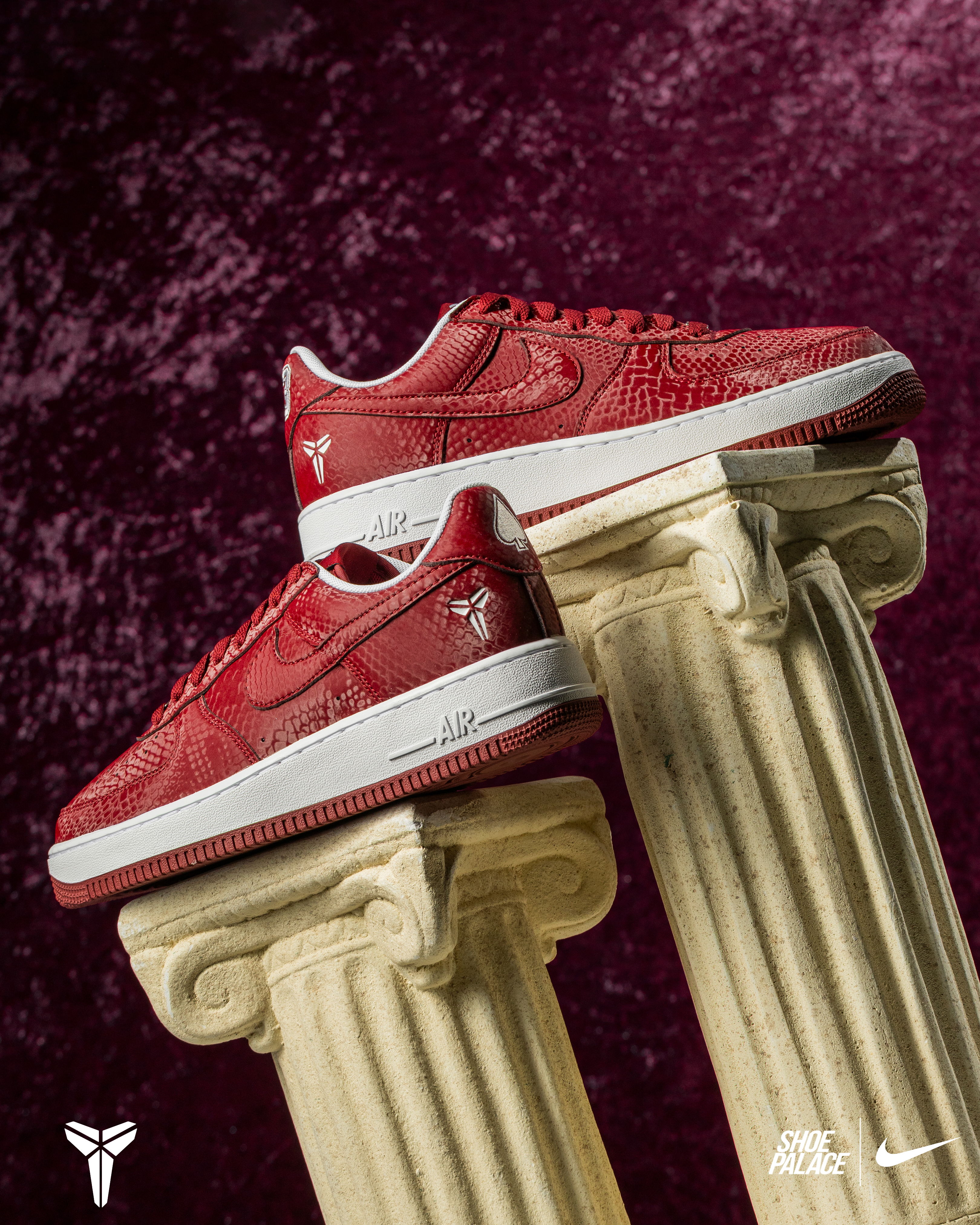Red sneakers displayed on columns against a textured background.