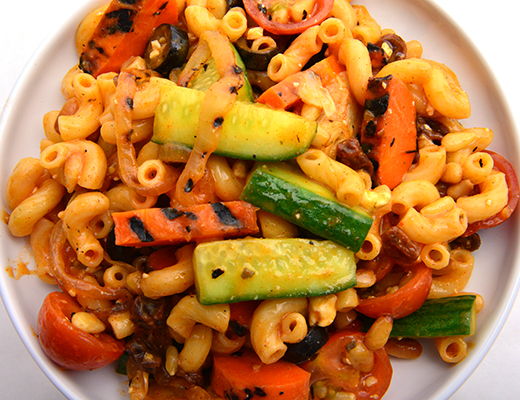 A plate of pasta mixed with grilled vegetables.
