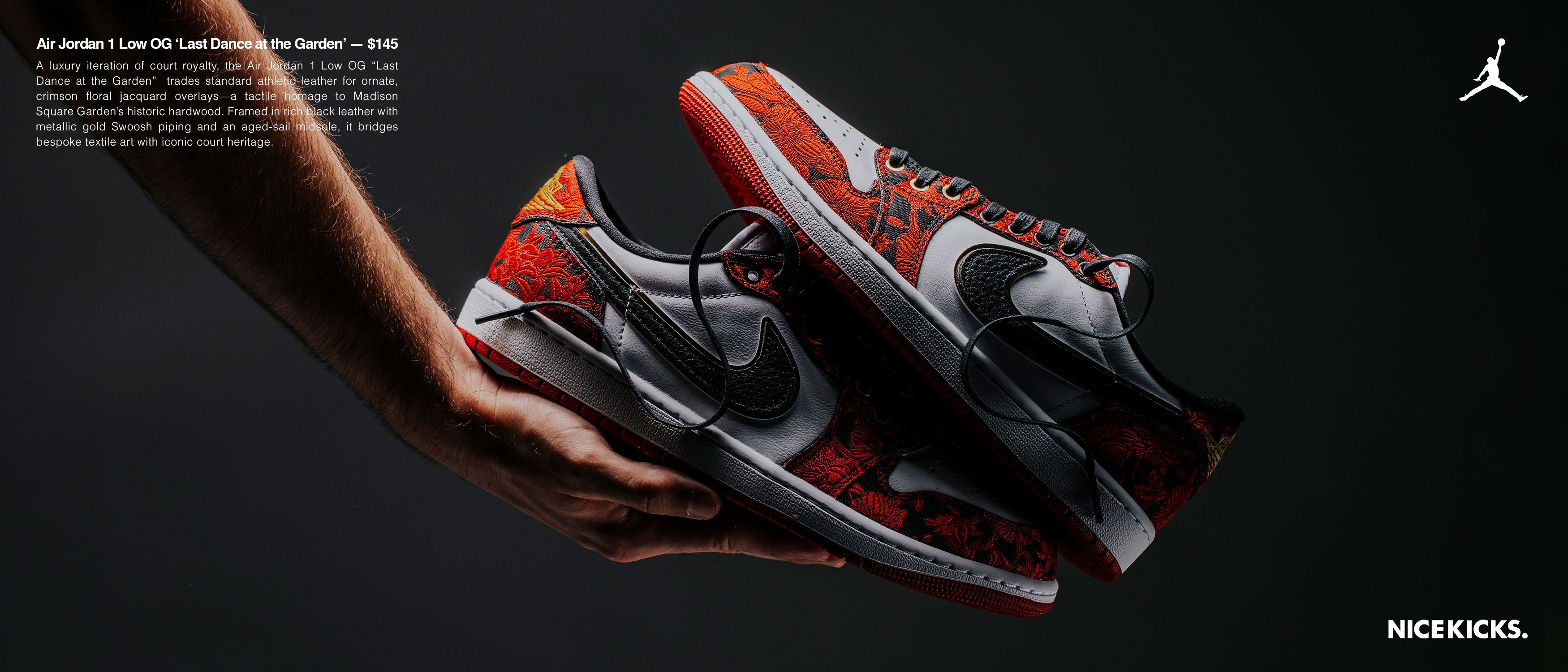 A hand holding a pair of red and black sneakers on a dark background.
