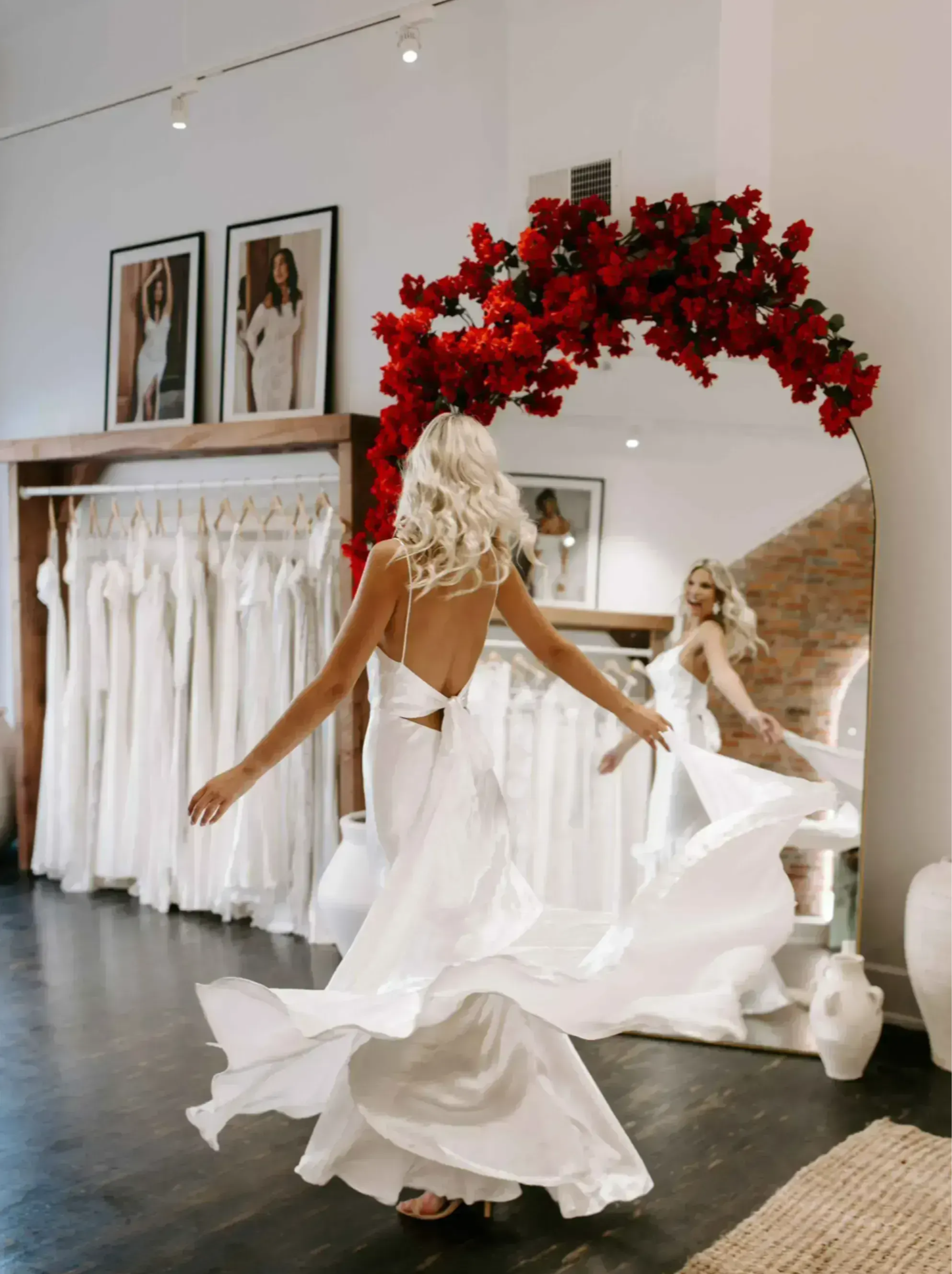 Bride twirling in front of mirror with featured red floral arrangement