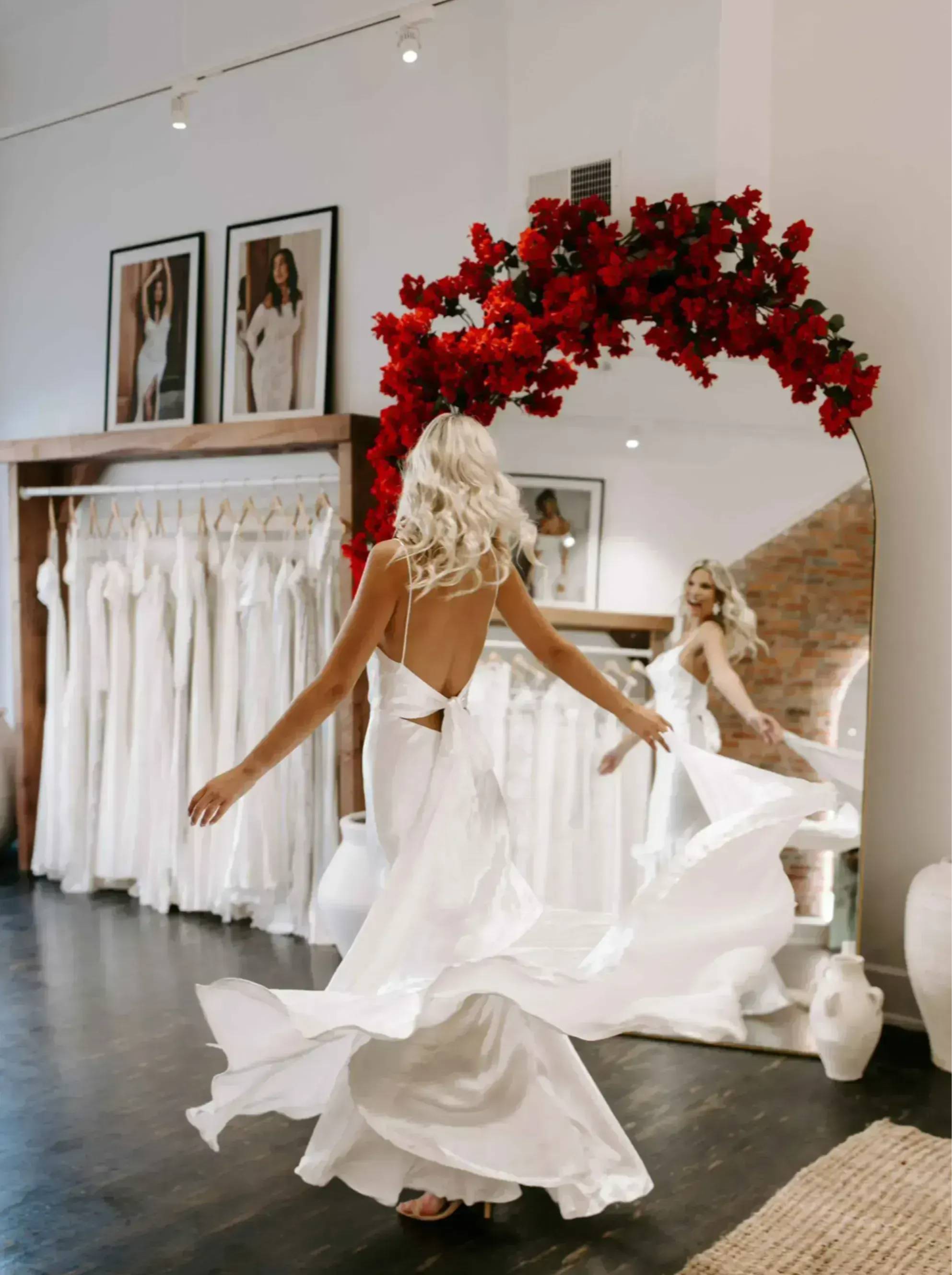 La mariée virevolte devant le miroir avec un arrangement floral rouge.