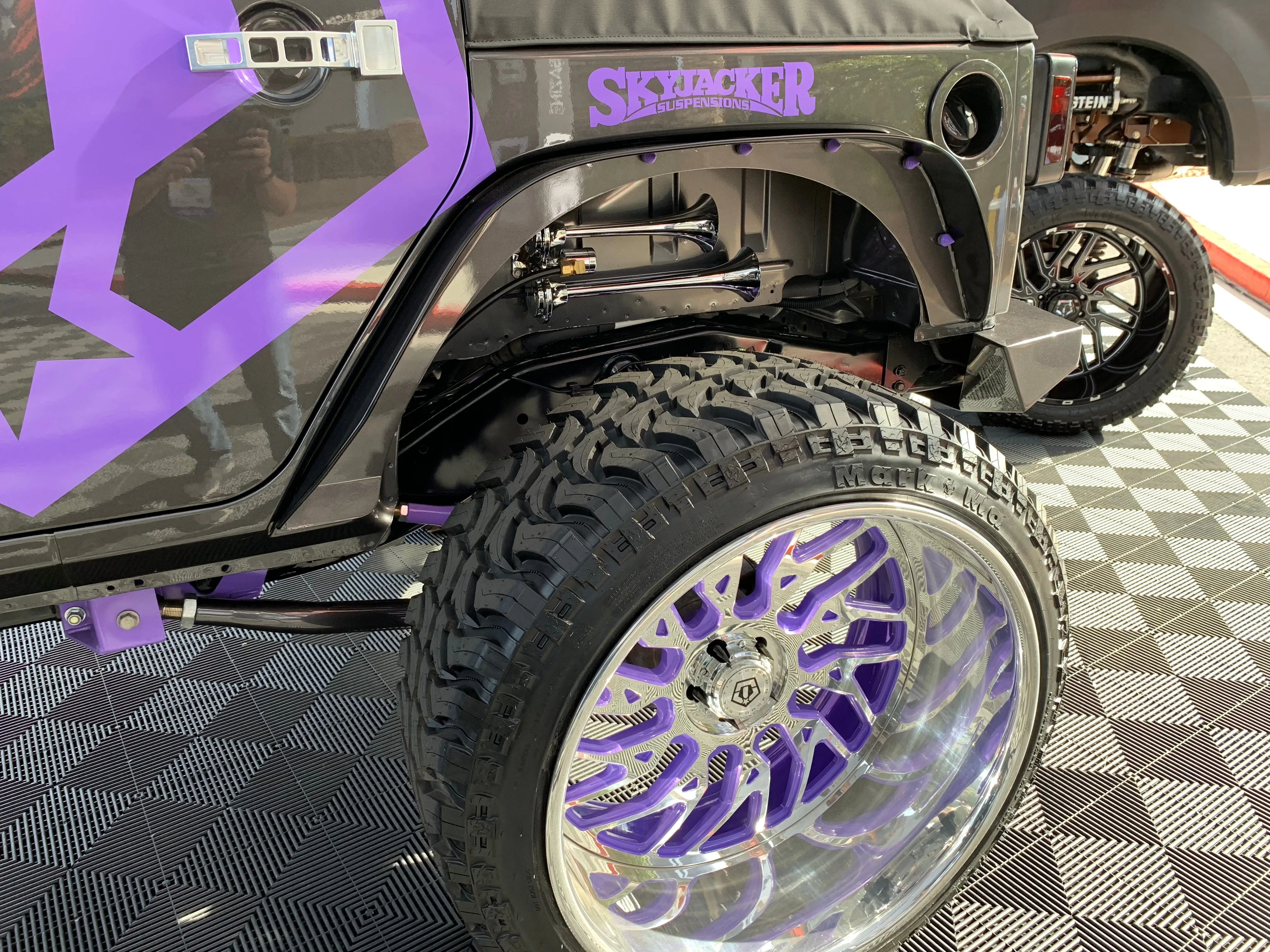 Close-up chrome PsychoBlasters trumpet air horns mounting bracket grille bumper area Janessa's Jeep Wrangler onboard air detail photo 3