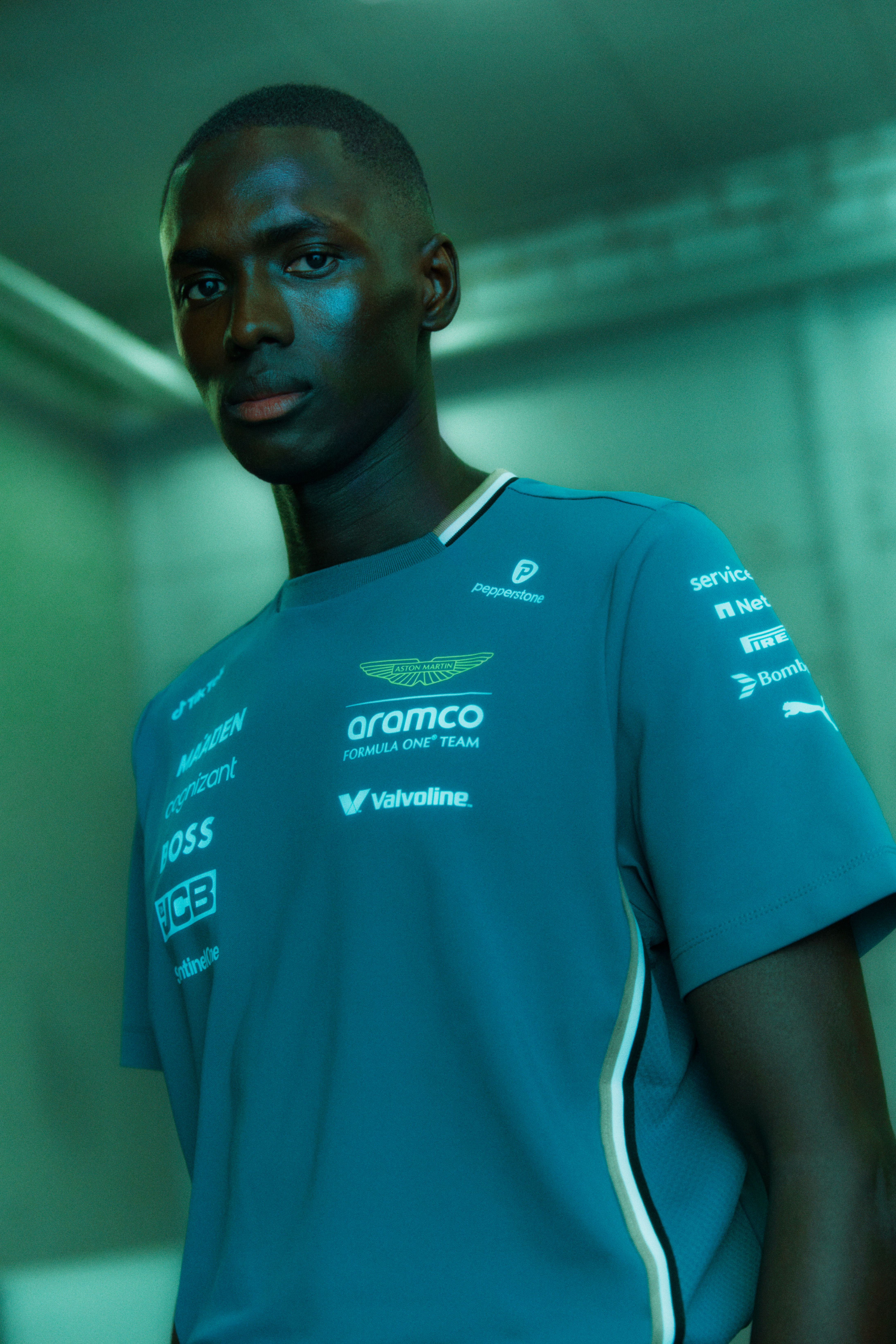 A person in a blue shirt with logos, standing in a modern setting.