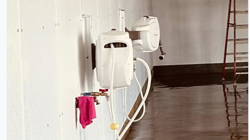 Two white hand dryers mounted on a wall, with a towel hanging nearby.