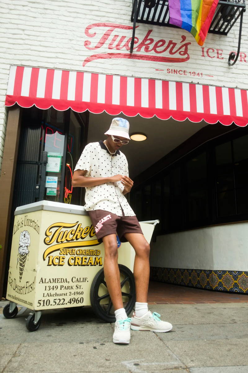 male model leaning against ice cream cart wearing nice cream sneakers