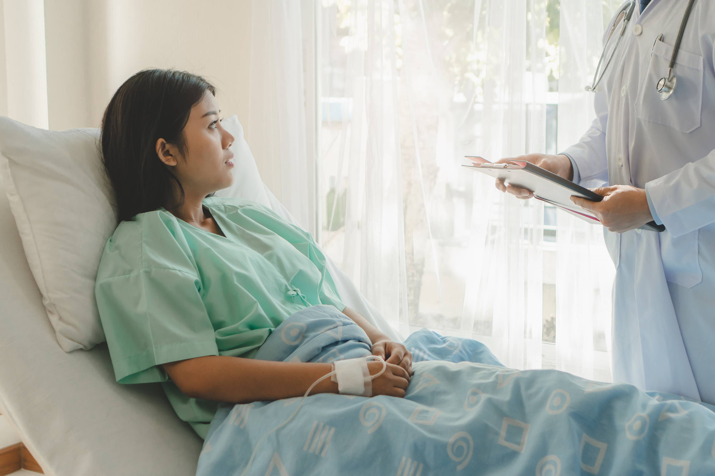 Woman in hospital bed, doctor taking care of patient