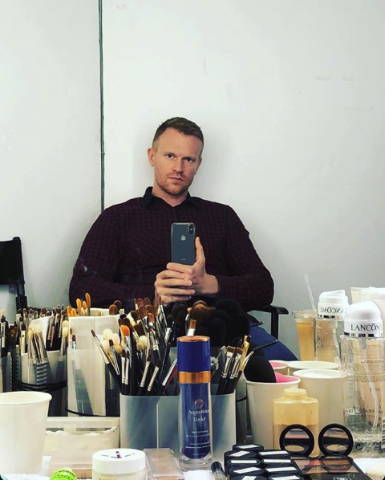 Celebrity makeup artist Benjamin Puckey, selfie, desk with lots of beauty products, serious face