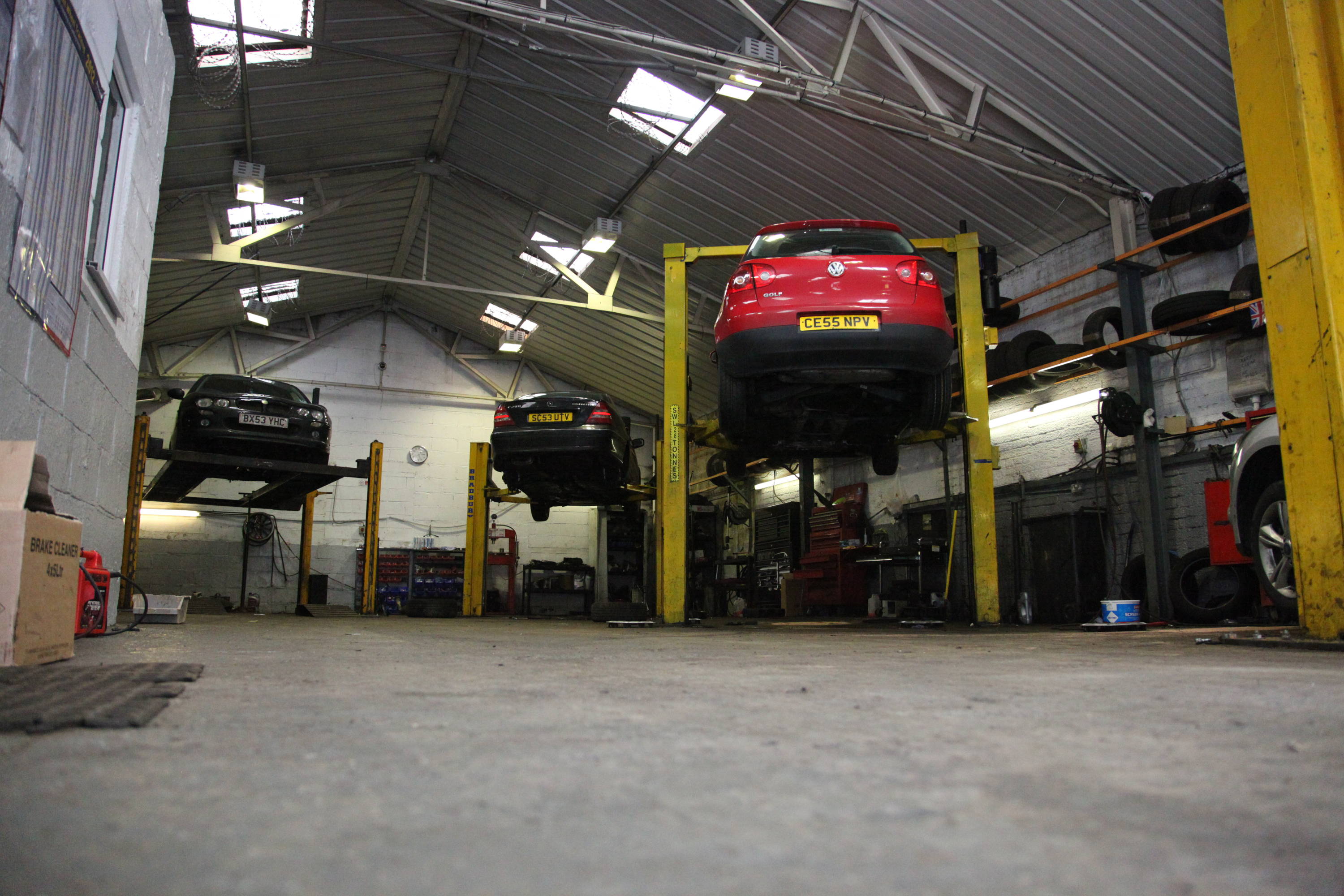 Inside car garage with three cars lifted up on steel frames 