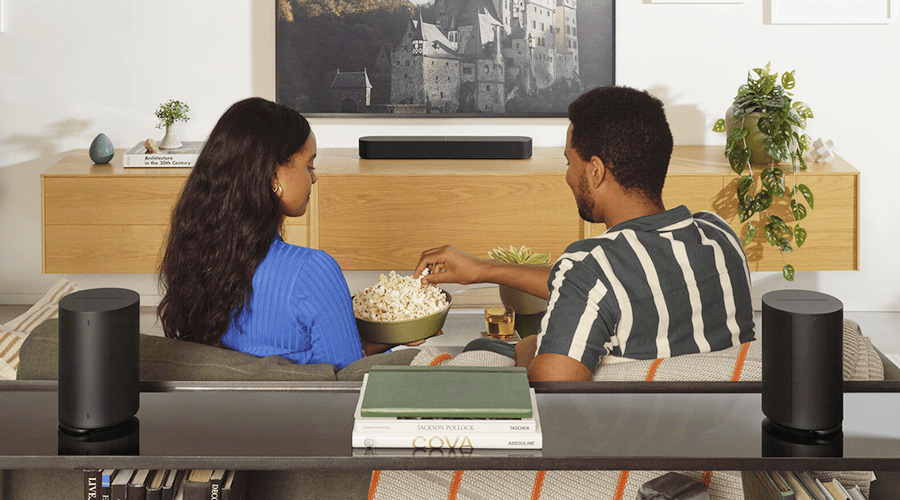 A couple sharing popcorn while watching TV at home.