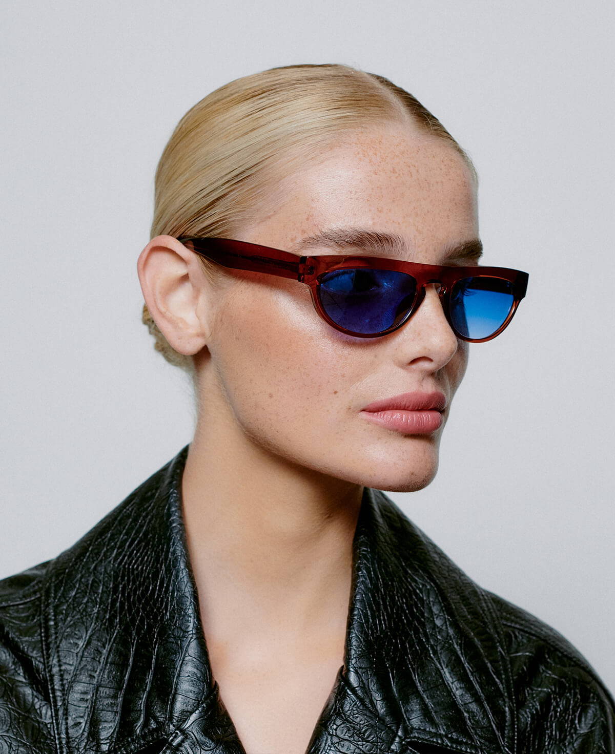 A picture of a model wearing the A.Kjaerbede  Jake sunglasses in Smoke Brown with blue lenses.