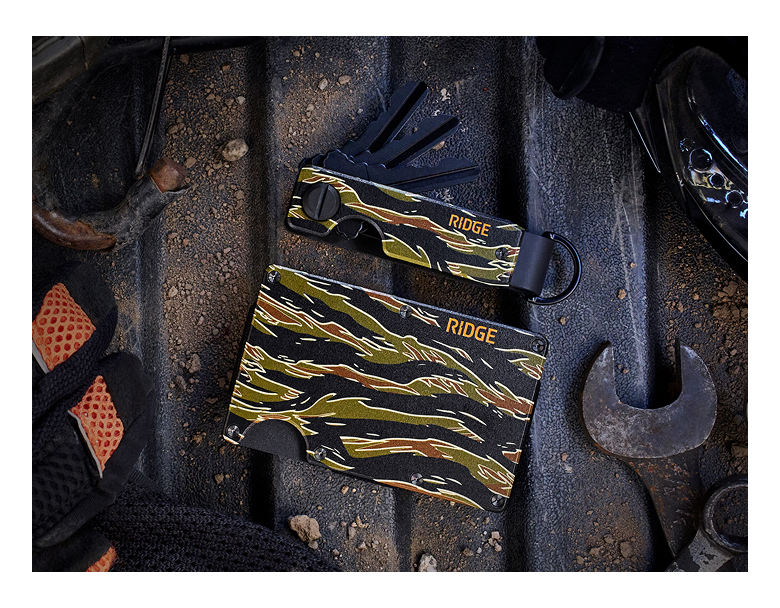 Camouflage wallet and gloves on a workshop floor with tools.