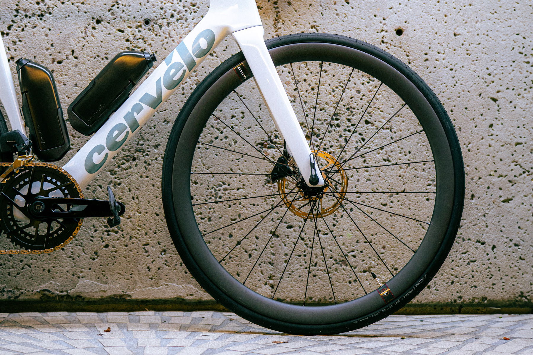 Close-up of a bike wheel against a textured concrete background.