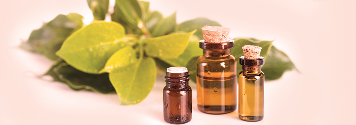 Bottles of essential oils with green leaves on a light background.