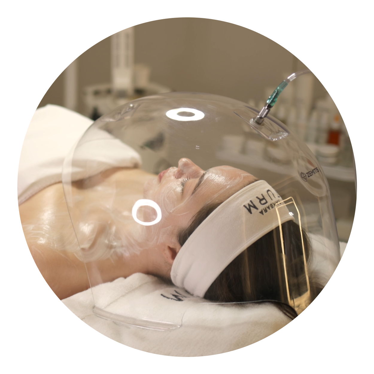 Person receiving a facial treatment under a dome-shaped device.