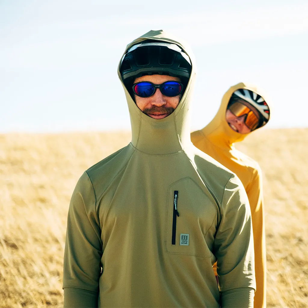 Two people in hoods and sunglasses outdoors, one in yellow and one in green.