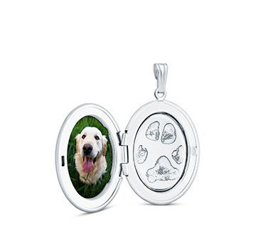 A silver locket featuring a dog's photo and paw prints inside.