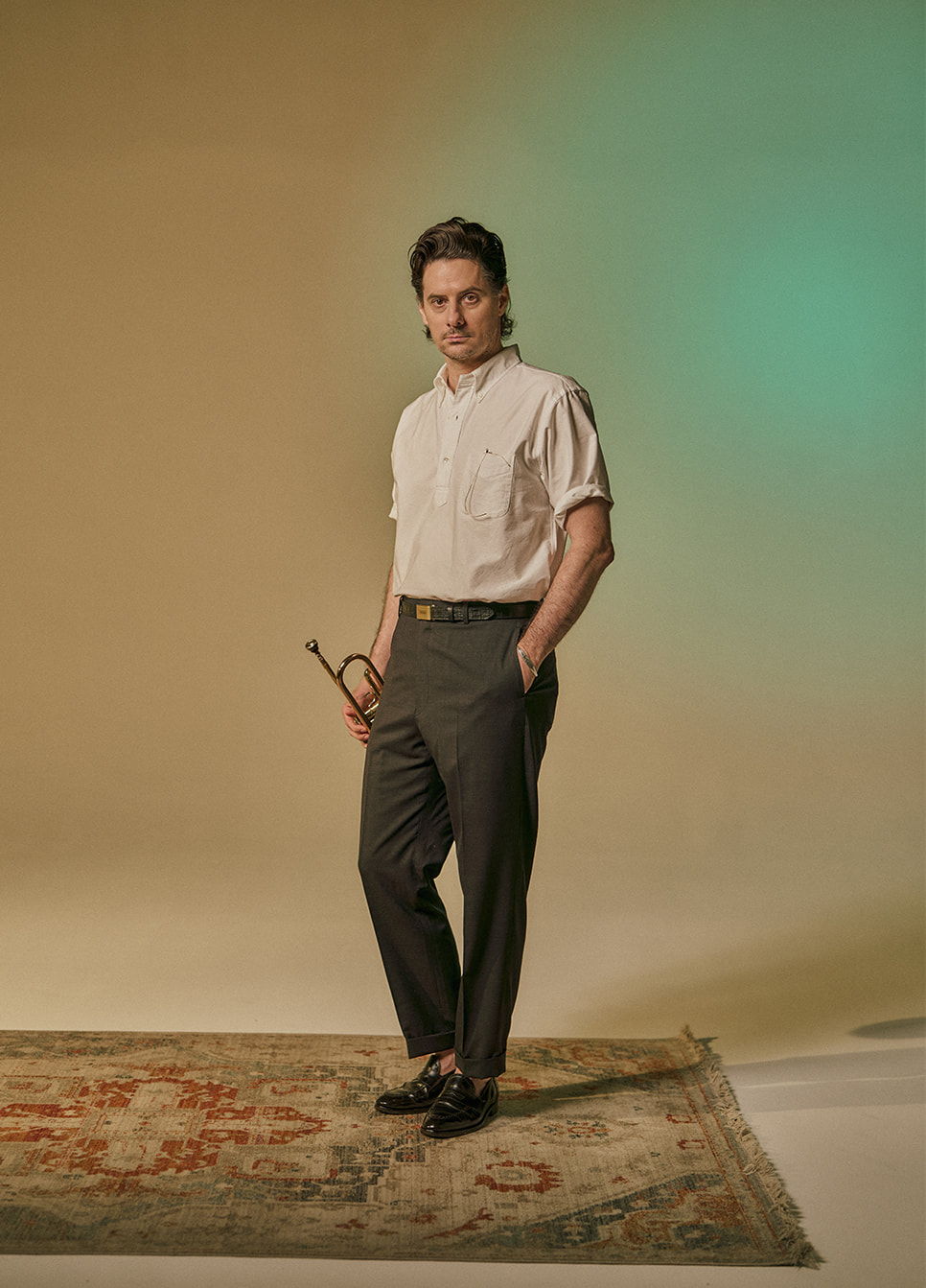 A person standing on a rug, wearing a short-sleeve shirt and trousers.
