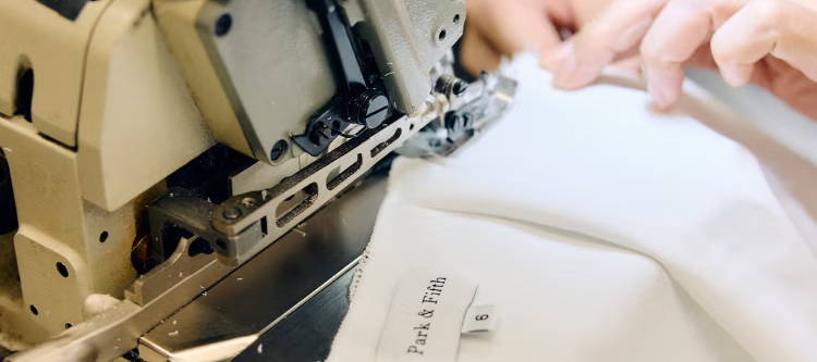 Person sewing a Park & Fifth dress on a sewing machine.