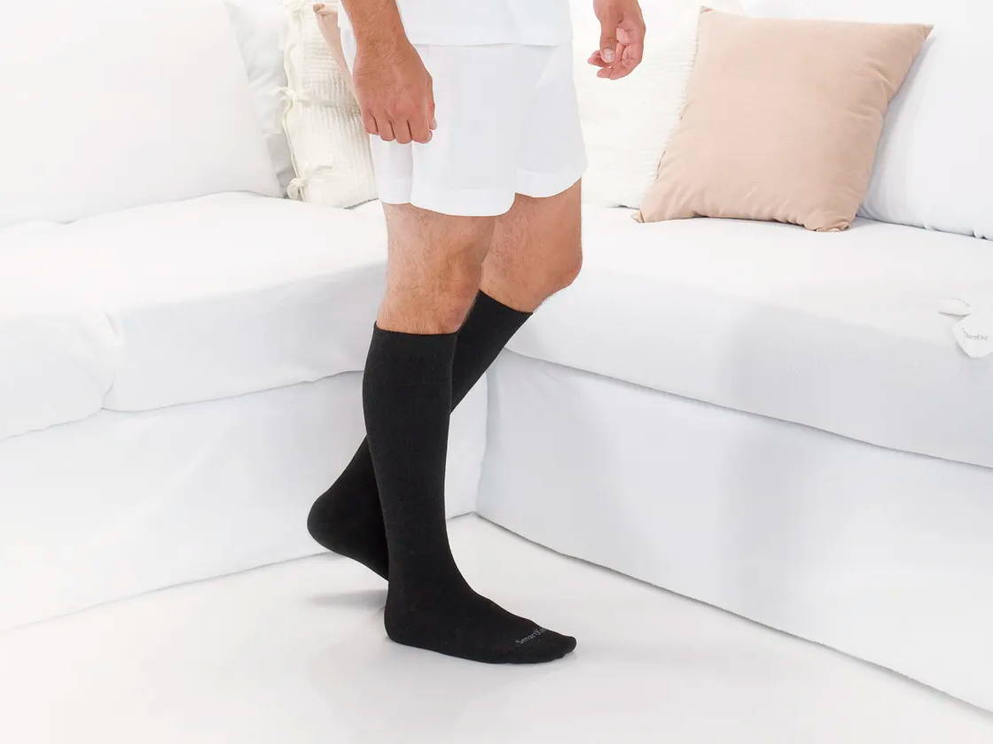 Man standing wearing SmartKnit Over-the-Calf Seamless Socks