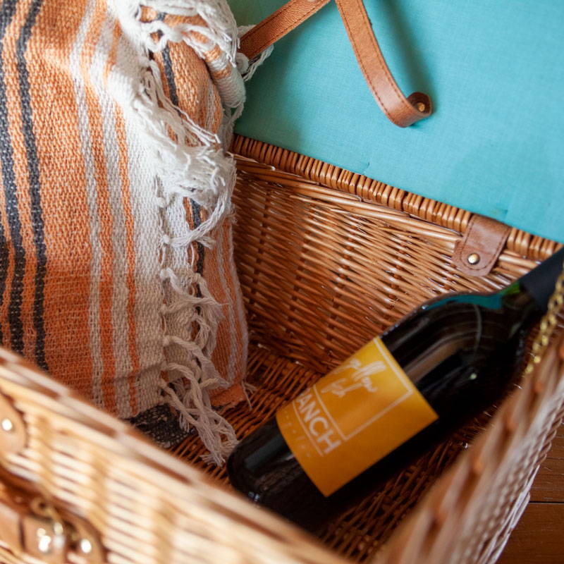 Picnic basket with a bottle of wine and blanket.