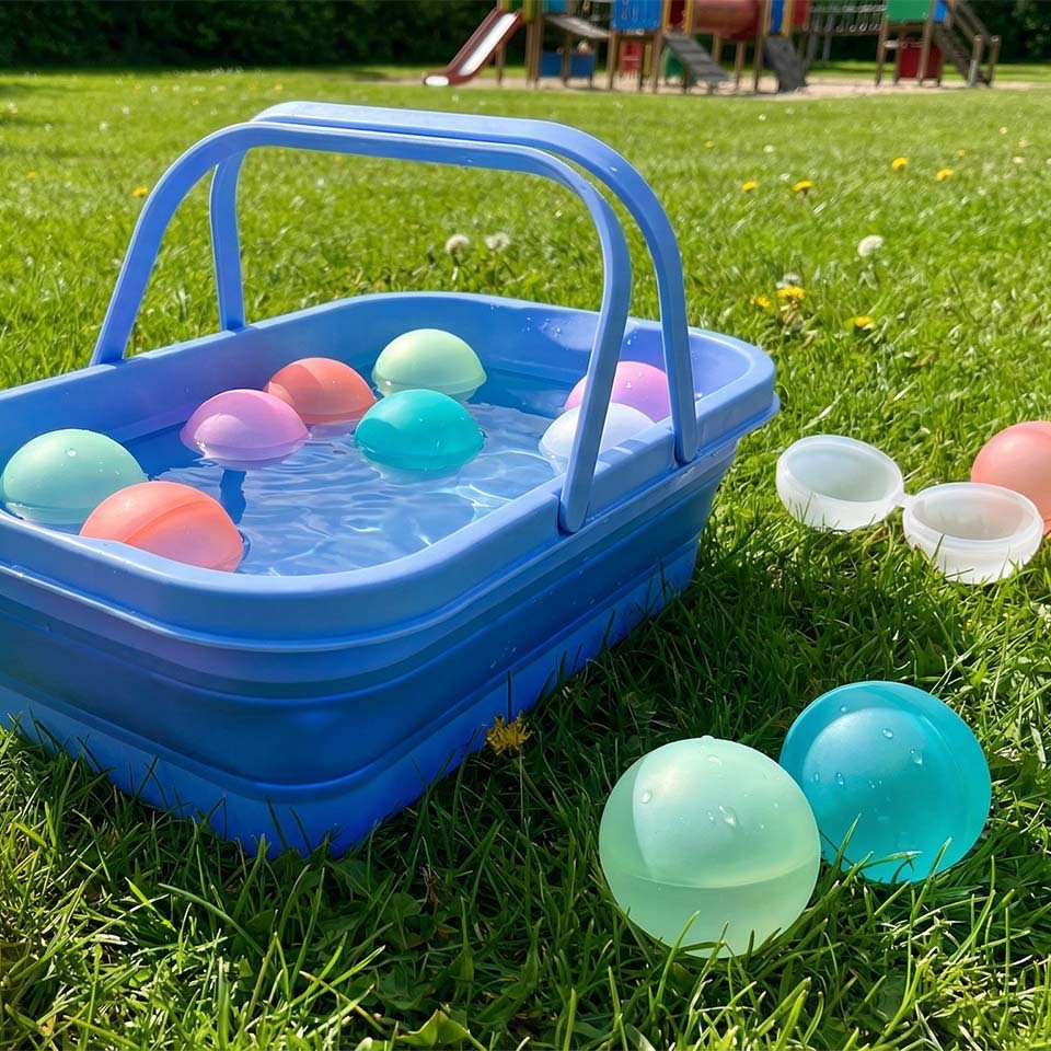 A blue basket with colorful balls on grass in a playground setting.