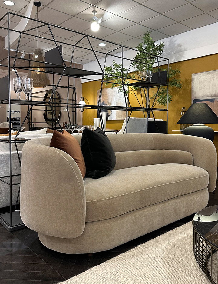 A modern beige couch with decorative pillows in a stylish interior furniture store.