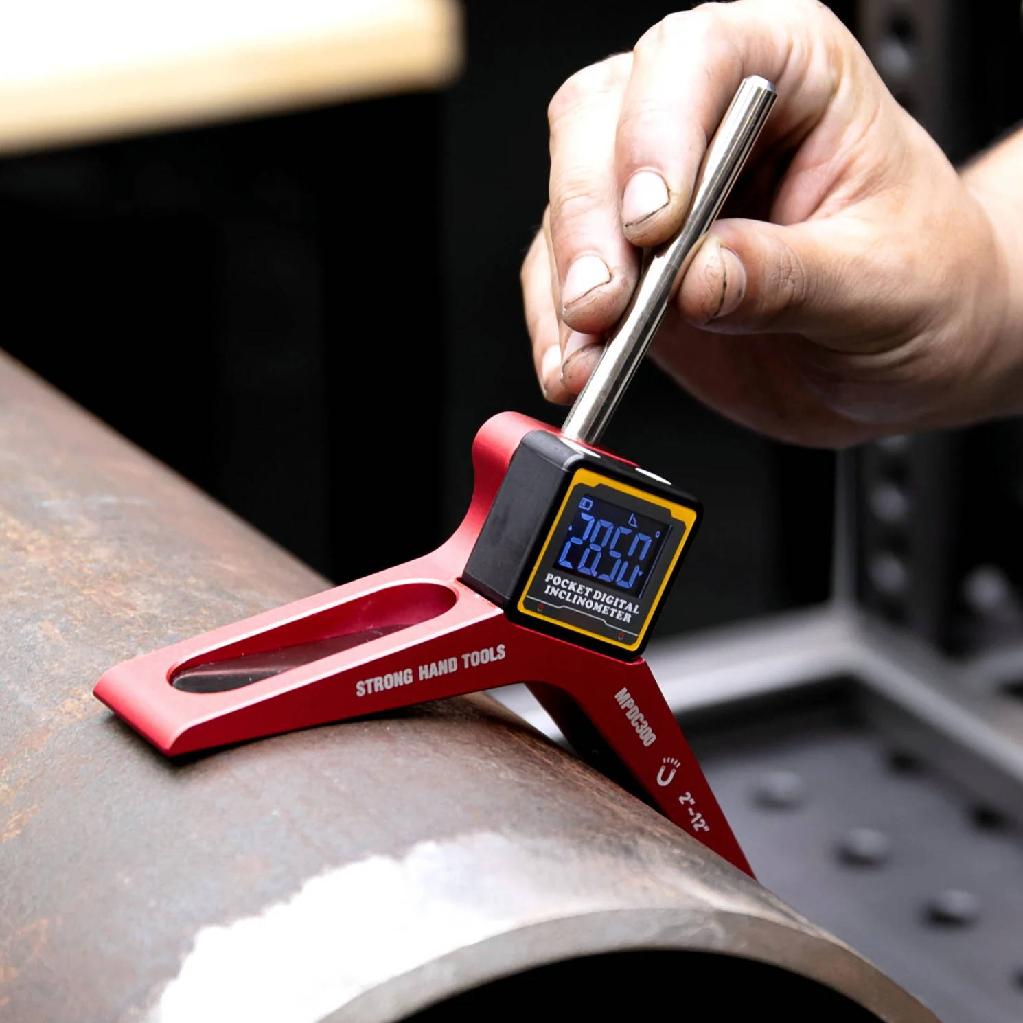 A hand using a gauge on a metal pipe for measurement.
