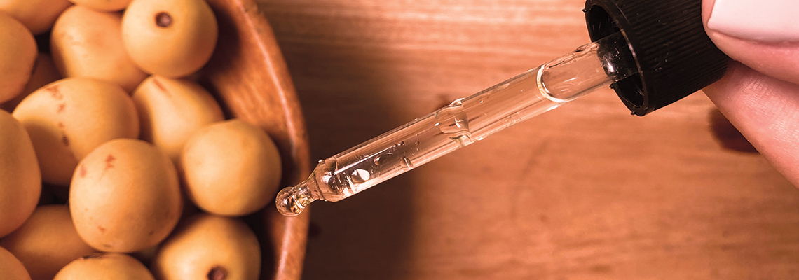 A dropper dispensing liquid over a bowl of olives.