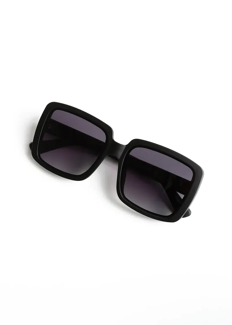 A pair of oversized, vintage inspired sunglasses with black frames and tinted lenses.