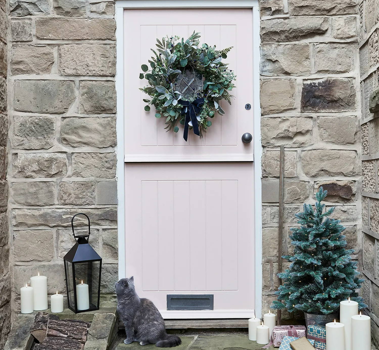 Pink front door with a Christmas wreath, lanterns and LED candles.