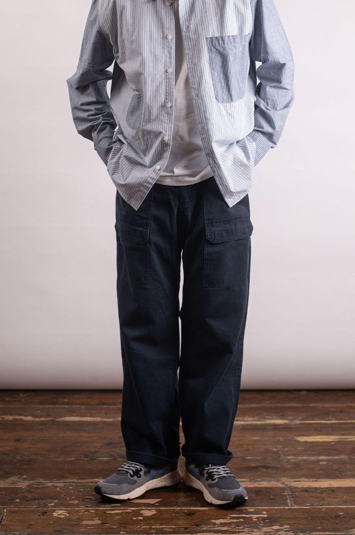 Person wearing a blue shirt, white t-shirt, dark pants, and sneakers.