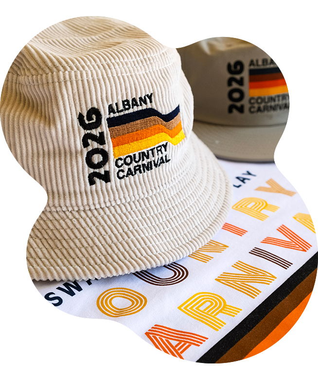 Cream corduroy bucket hat embroidered with the 2026 Albany Country Carnival logo featuring a multicoloured stripe design, sitting on a white screen printed t-shirt with a bold letter design in matching colours