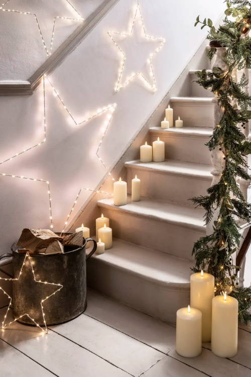 Staircase with a Christmas garland and candles and star lights.