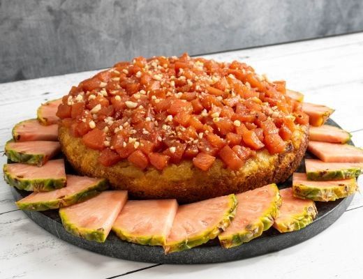 A round cake topped with fruit, surrounded by sliced watermelon.