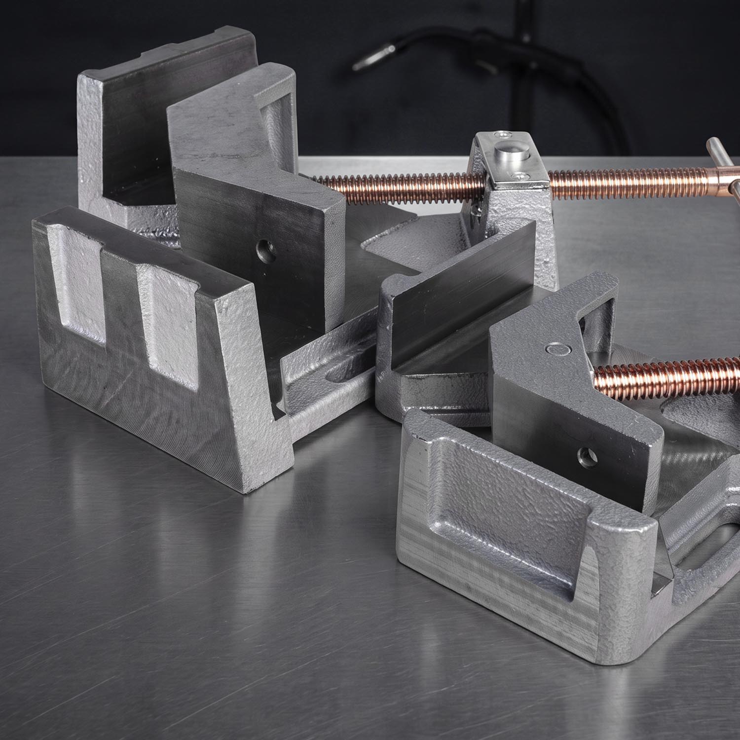 Metal clamps and fixtures arranged on a workbench surface.