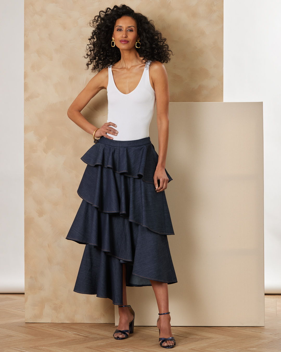 Model wearing a layered navy skirt and white top, posing against a neutral background.